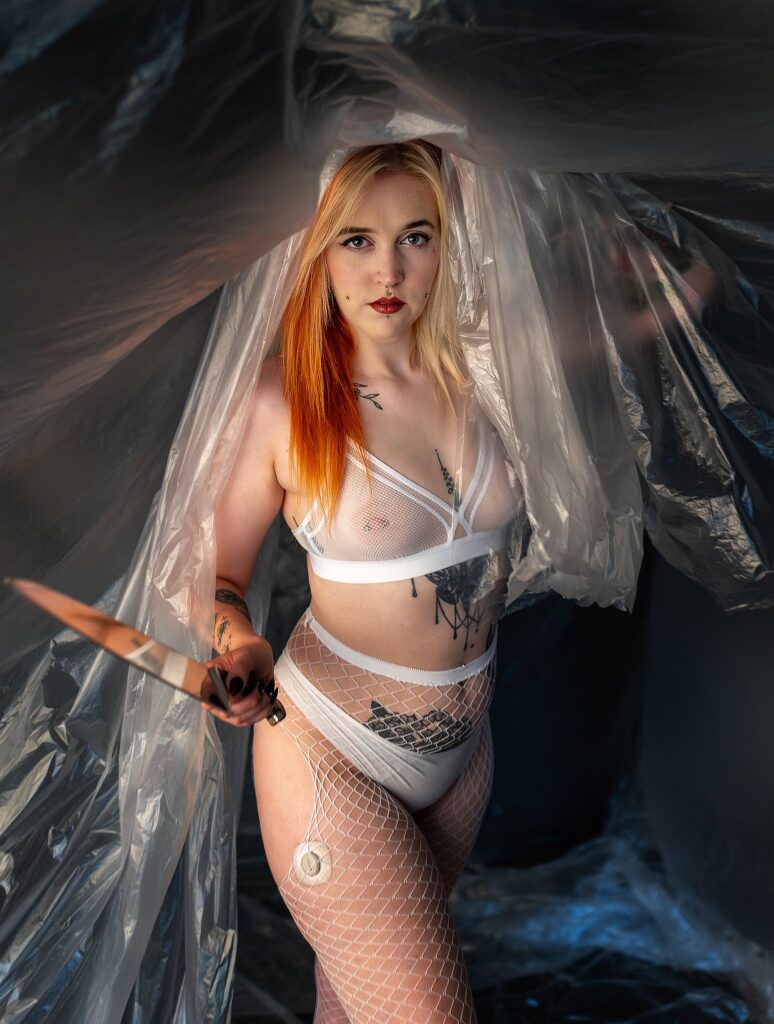 Abigail holding a knife, surrounded by plastic sheets, during her Dexter-inspired boudoir session.