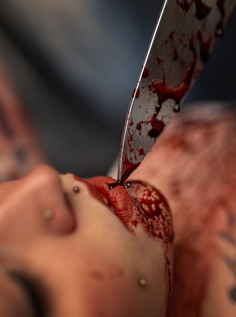 Close-up of a blood-smeared knife near Abigail’s face in the Halloween boudoir session.