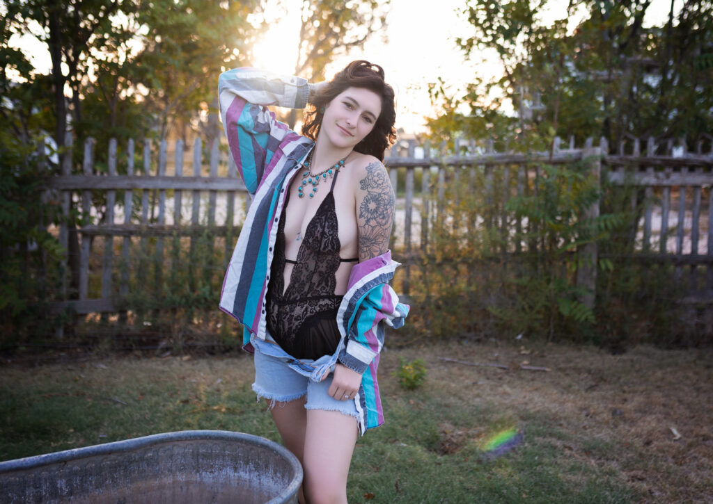 Thalia standing in a colorful jacket and lace bodysuit, showing off her unique style in a Western boudoir session