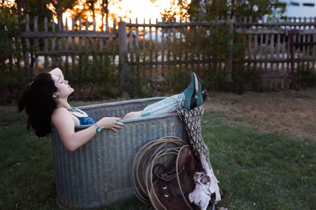 Thalia relaxing with her hair draped back, wearing turquoise jewelry, in a Western boudoir session setting